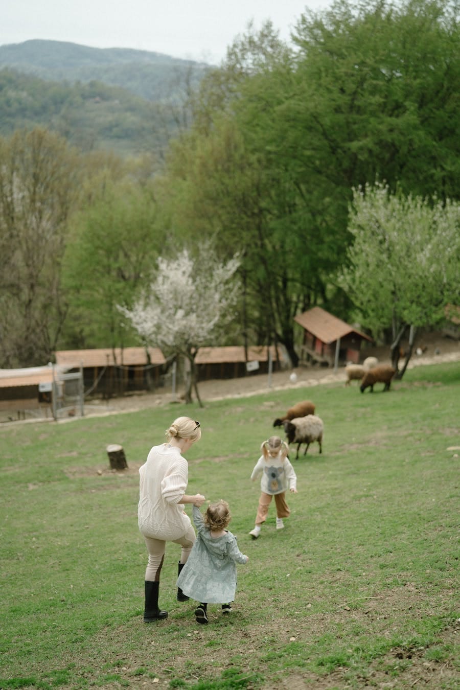A family enjoys a stroll with children on a lush green farm during springtime.
