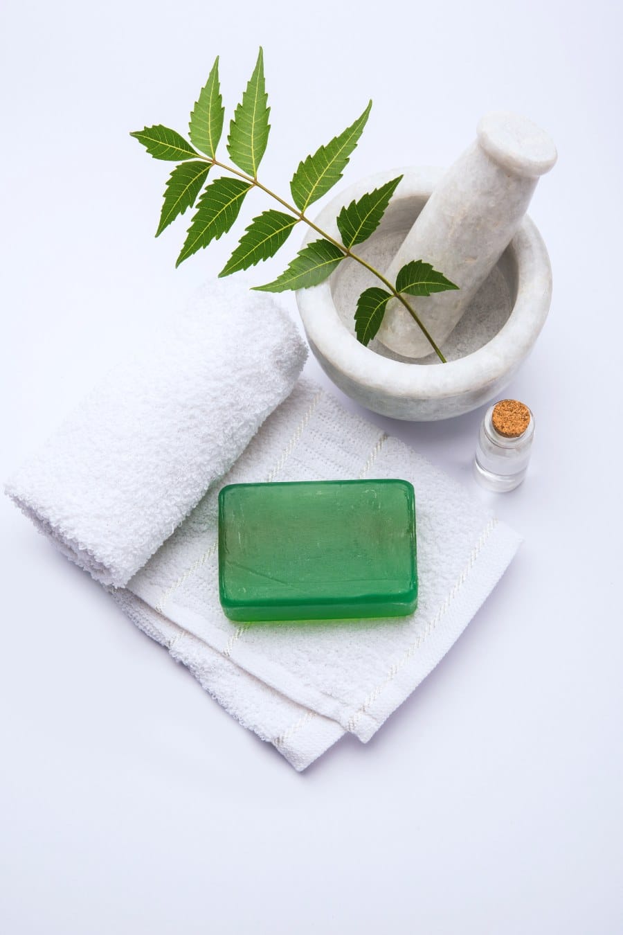 ayurvedic bath soap made up of Azadirachta indica or neem soap or sabun with mortar, neem leaves, neem oil and white towel, selective focus