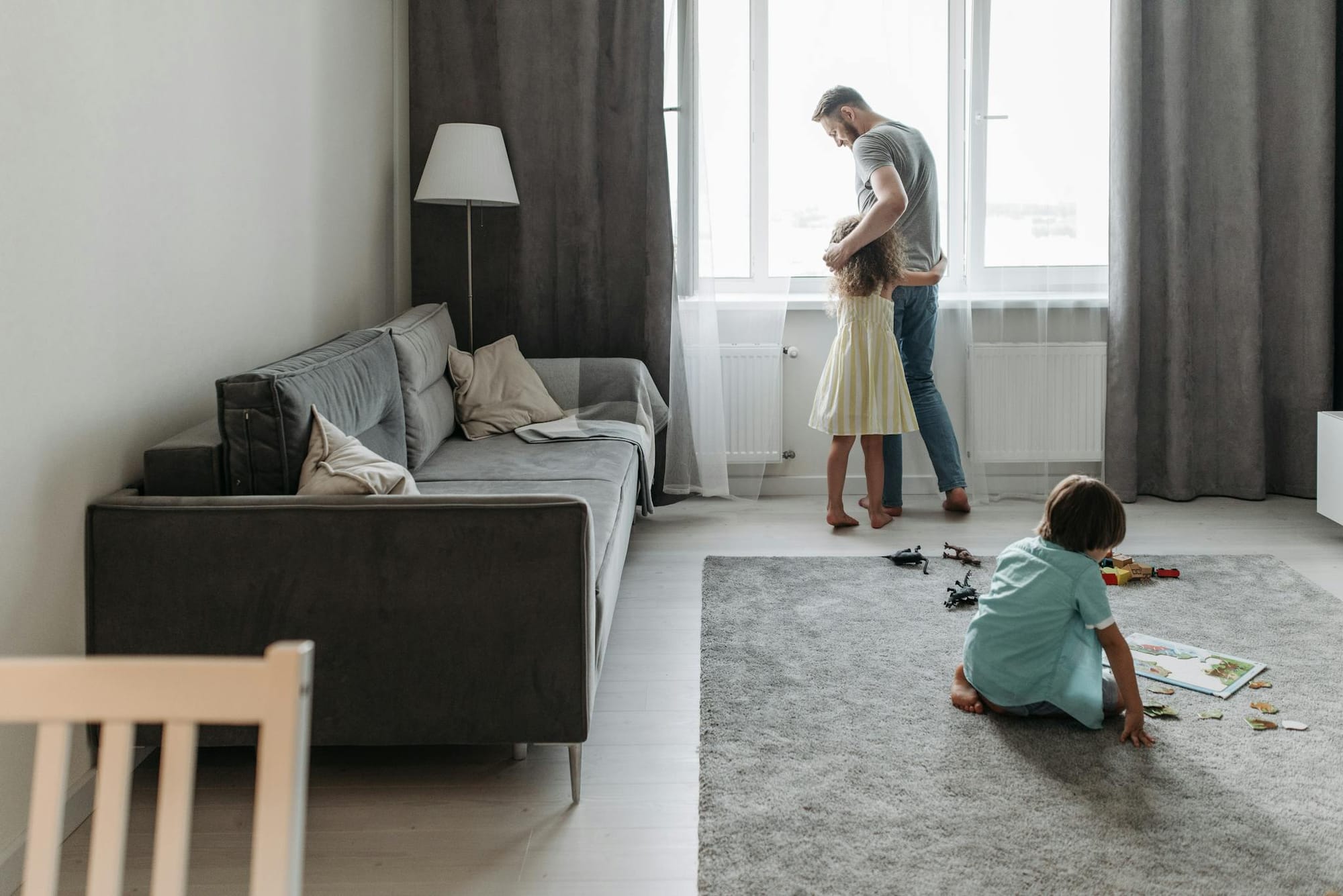 A father bonding with his children in a bright, modern living room setting.