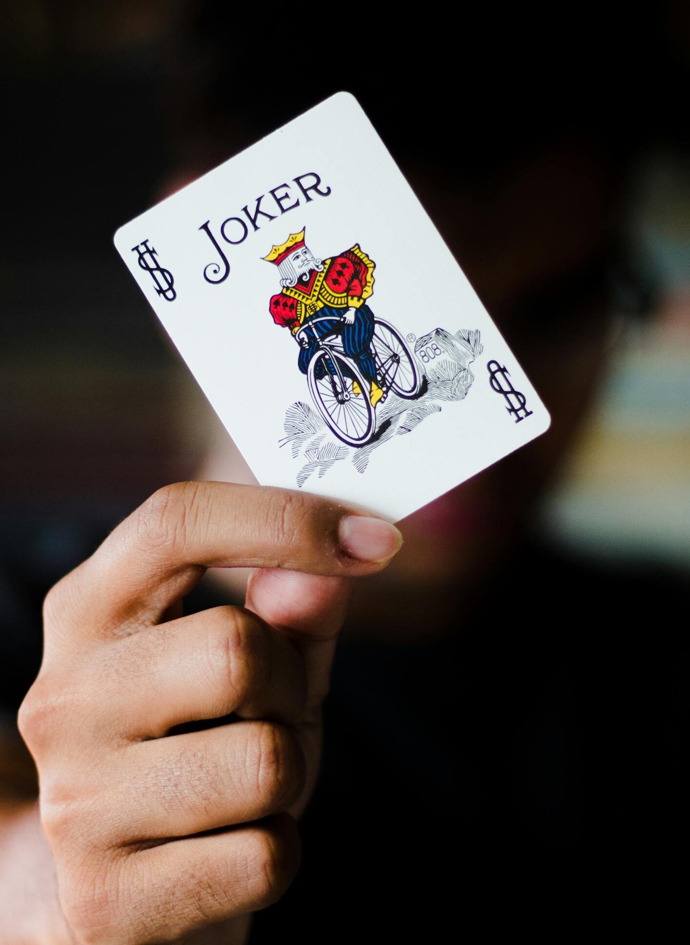 A focused shot of a person holding a Joker playing card, ideal for gambling themes.