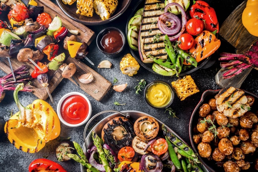 grilled vegetables and meats displayed on a dark table