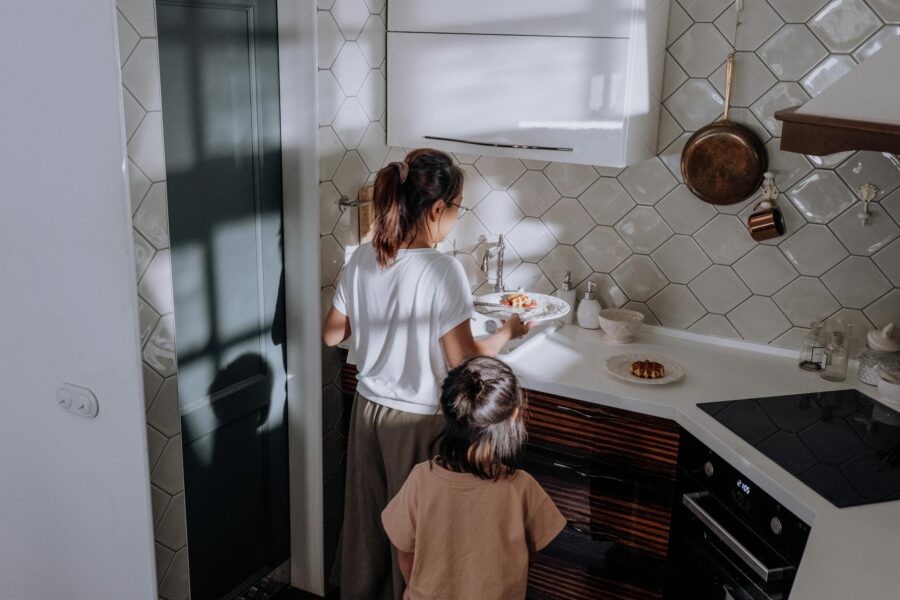 A mother and child collaborate on kitchen chores, creating a warm family moment.