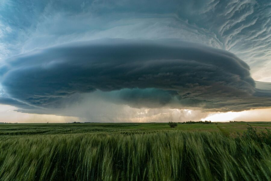 A powerful supercell storm looms over lush green fields in Saskatchewan, Canada.
