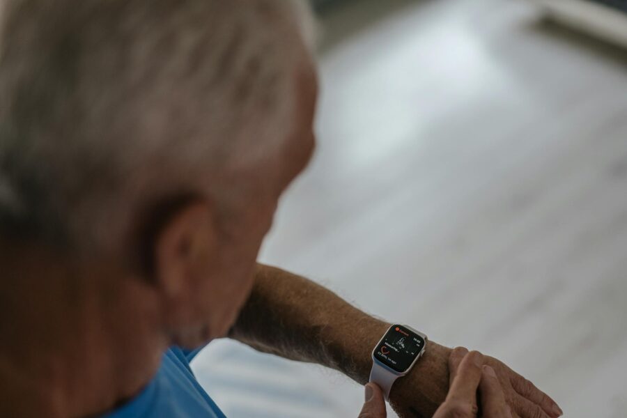 A senior man interacts with a smartwatch indoors, focusing on technology and lifestyle.