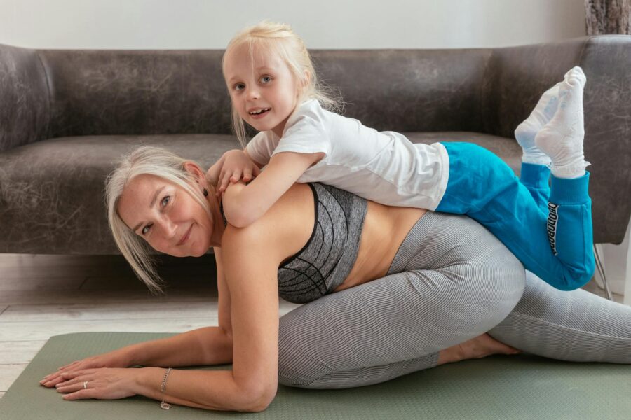 A senior woman and her young grandchild bonding during a fun yoga session indoors.