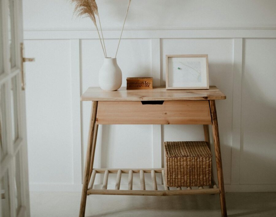 A serene minimalist interior features a wooden console table with pampas grass in a vase.
