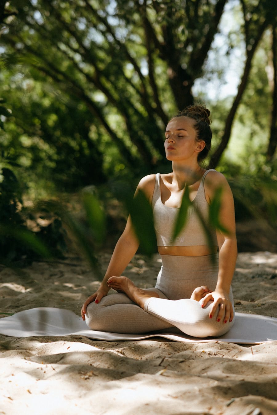 A woman meditating peacefully in a sunlit forest, embodying relaxation and mindfulness.