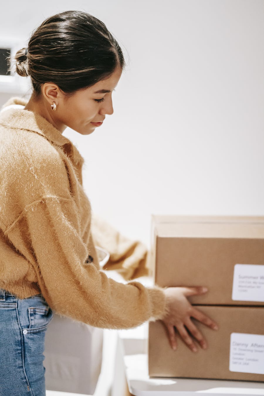 A young woman arranges delivery boxes at home, symbolizing online shopping and logistics.