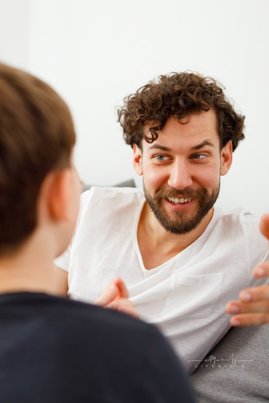father talking to his son on couch while smiling