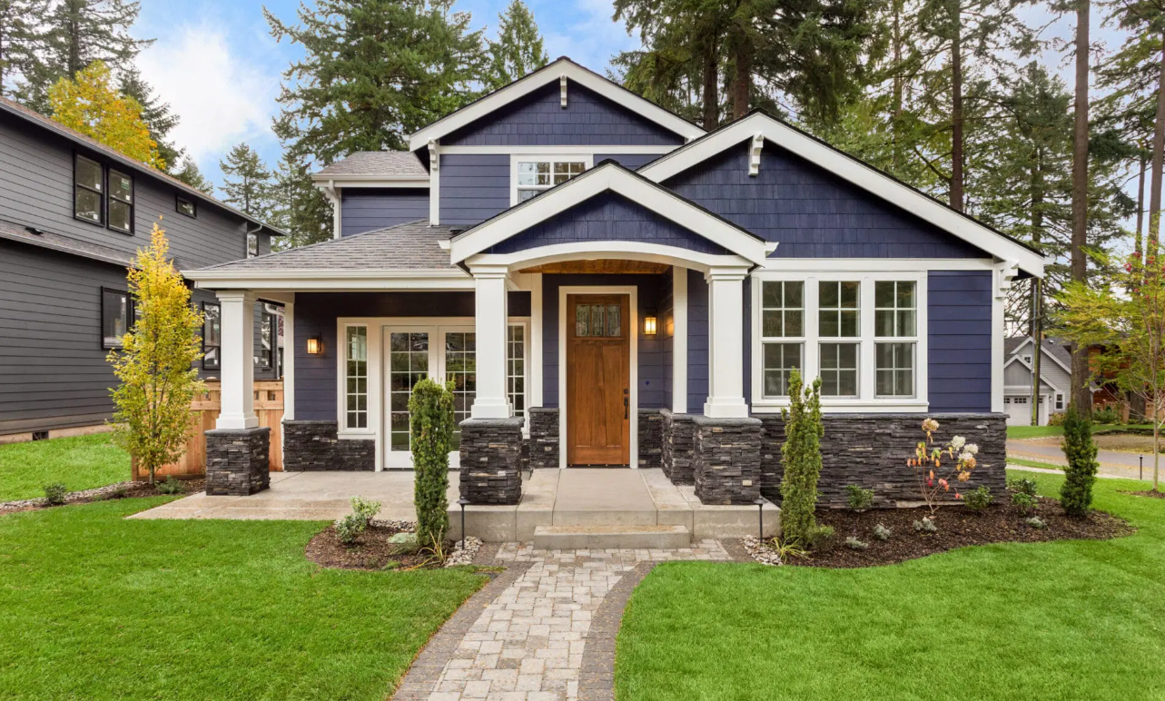 blue house with a timber door, green grass, and well landscaped