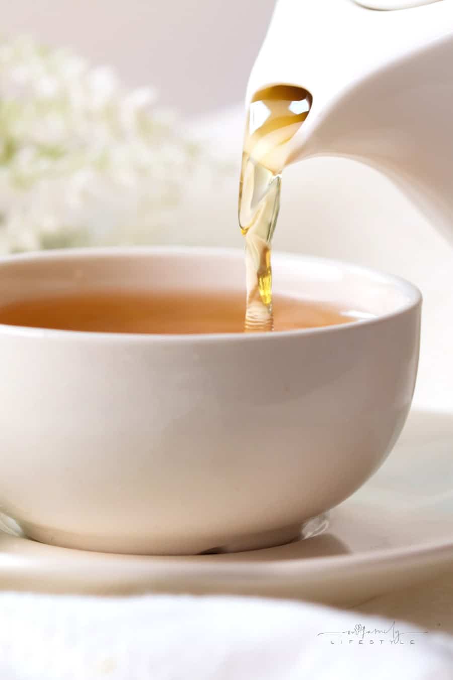 pouring hot tea into a white cup and saucer