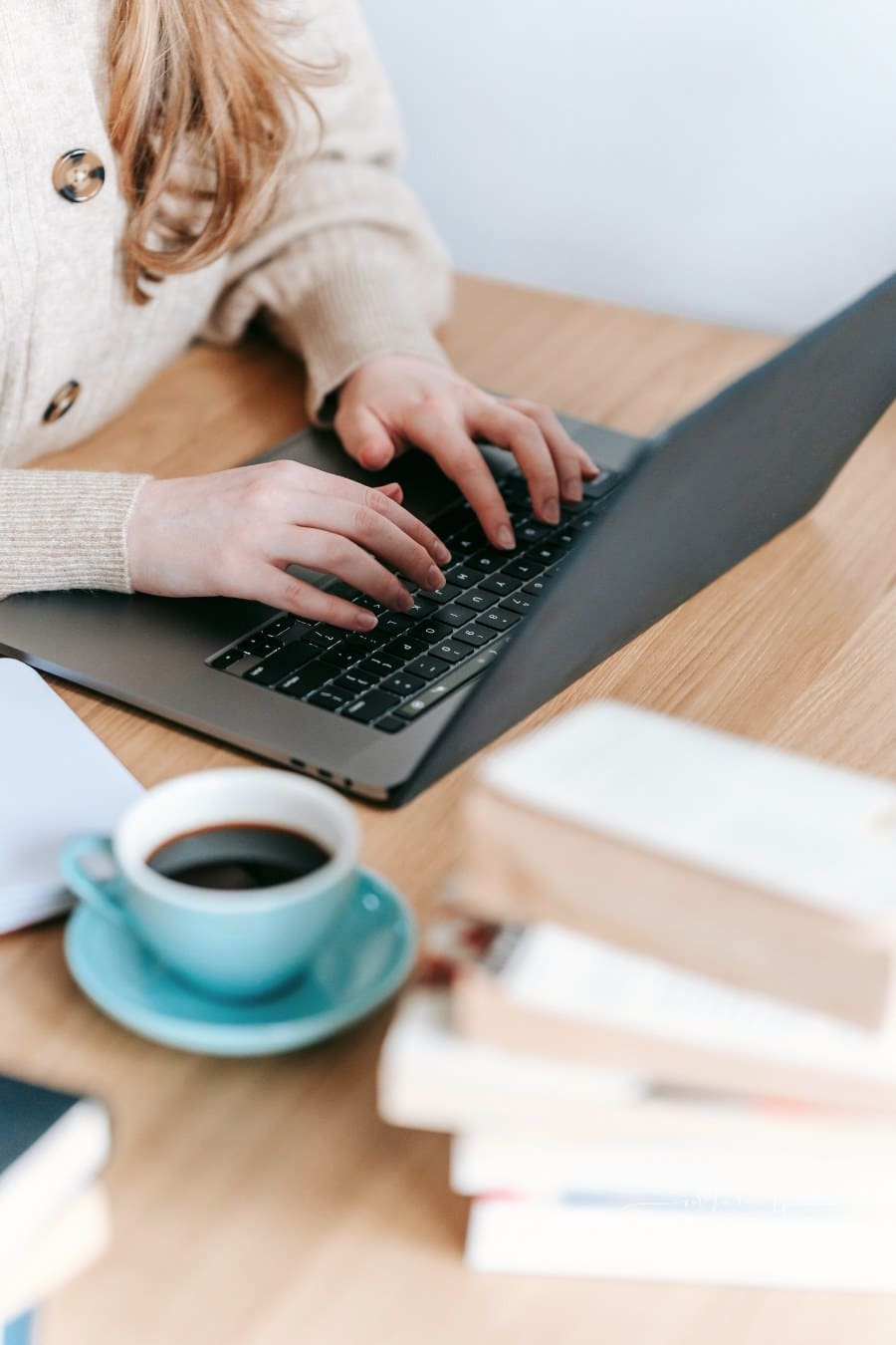woman typing on a laptop with cup of coffee nearby