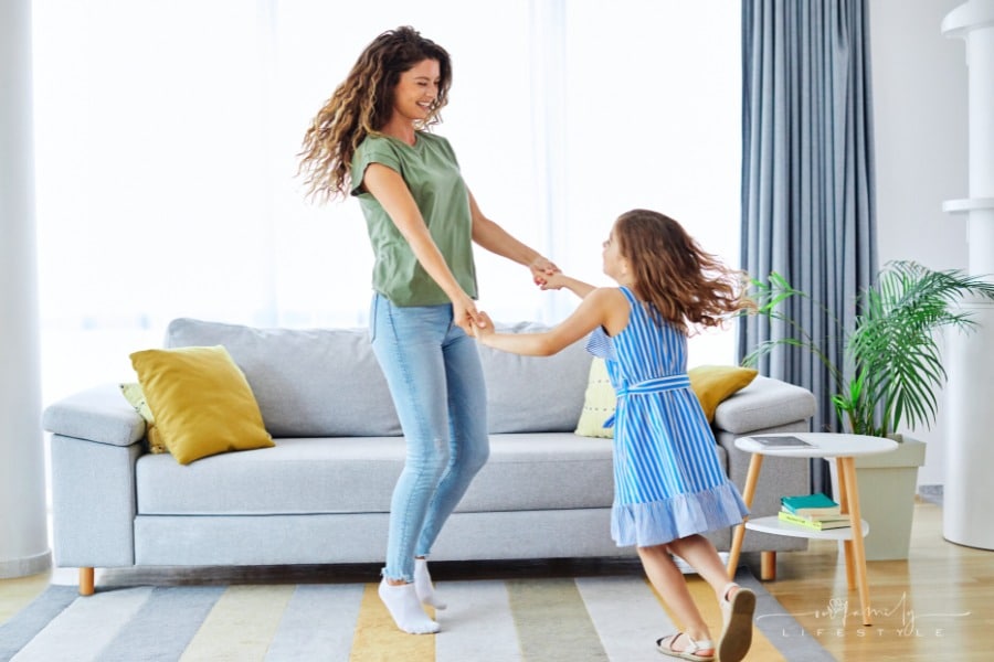 mom dancing with young daughter with both laughing