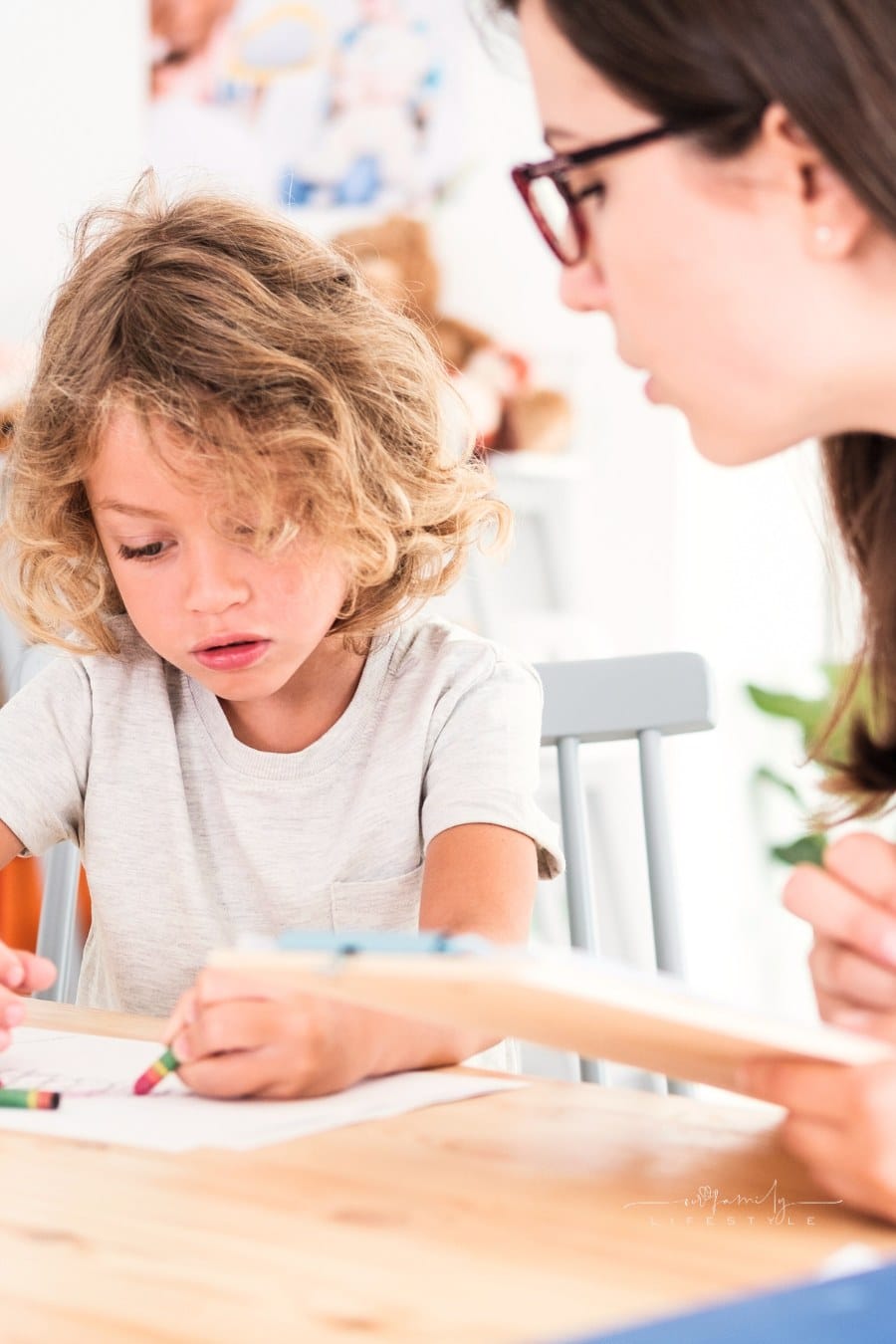 A psychotherapist watching a child draw pictures with crayons during an evaluation