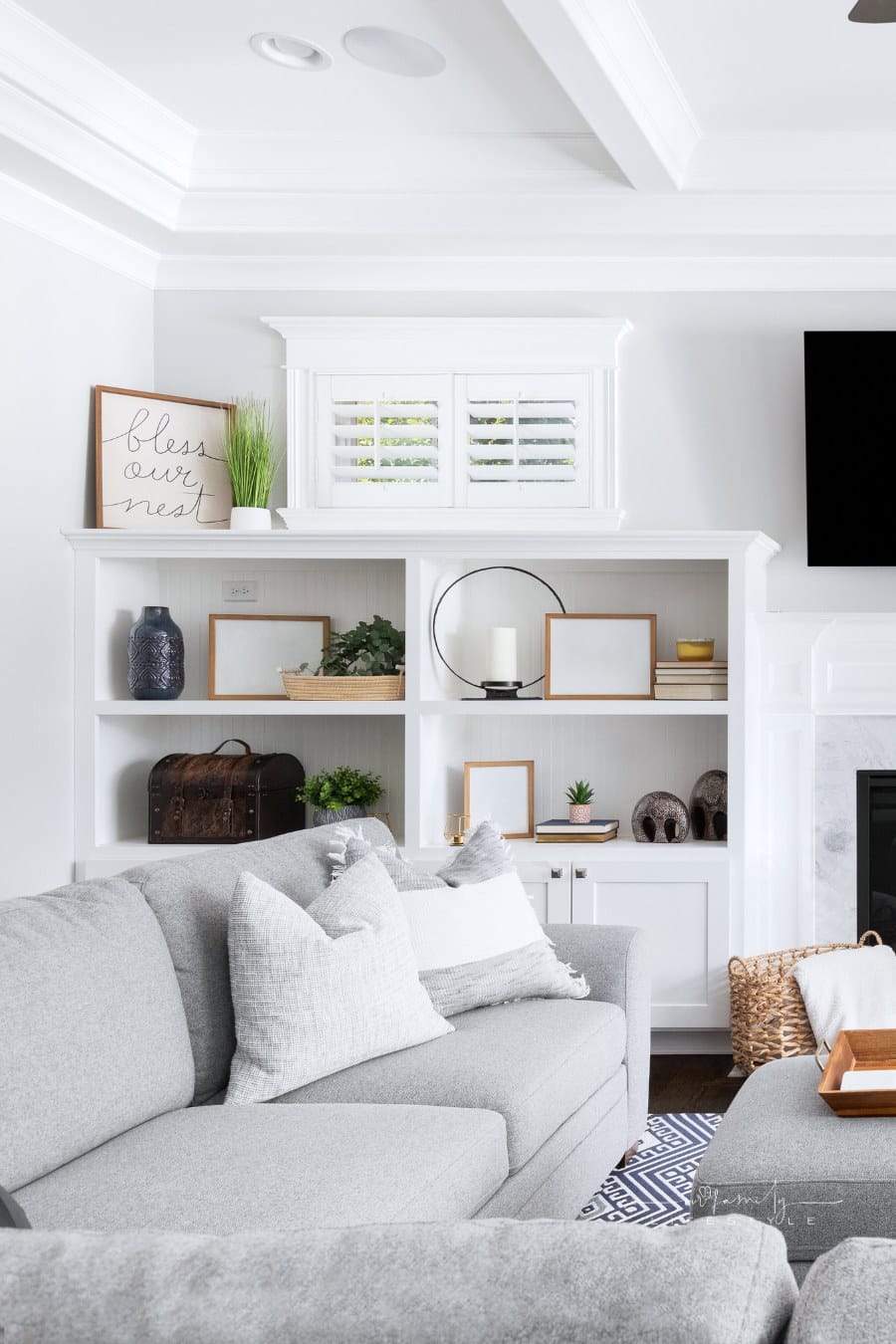 A living room's built-in shelving with a fireplace, television, and decorations.