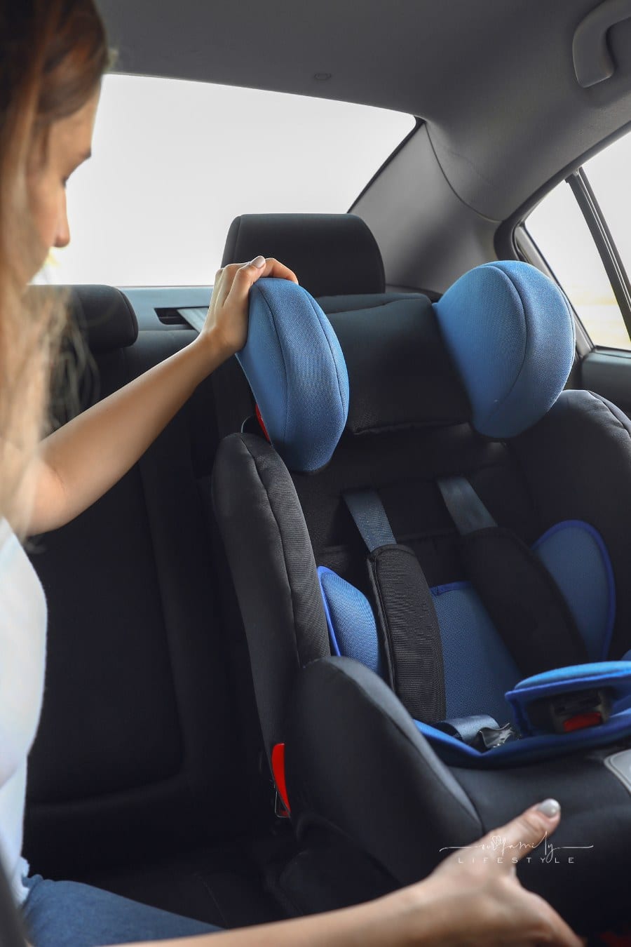Young Woman installing Safety Seat for Child in Car