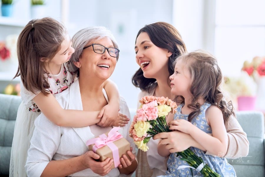 Grandma, Mom, and young daughters celebrating Mother's Day with gifts and flowers