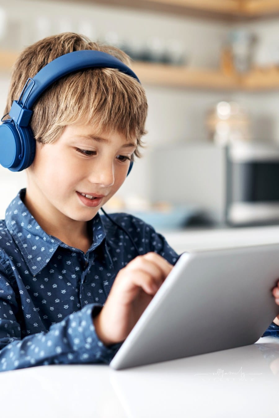 Shot of an adorable little boy wearing headphones while using a digital tablet at home