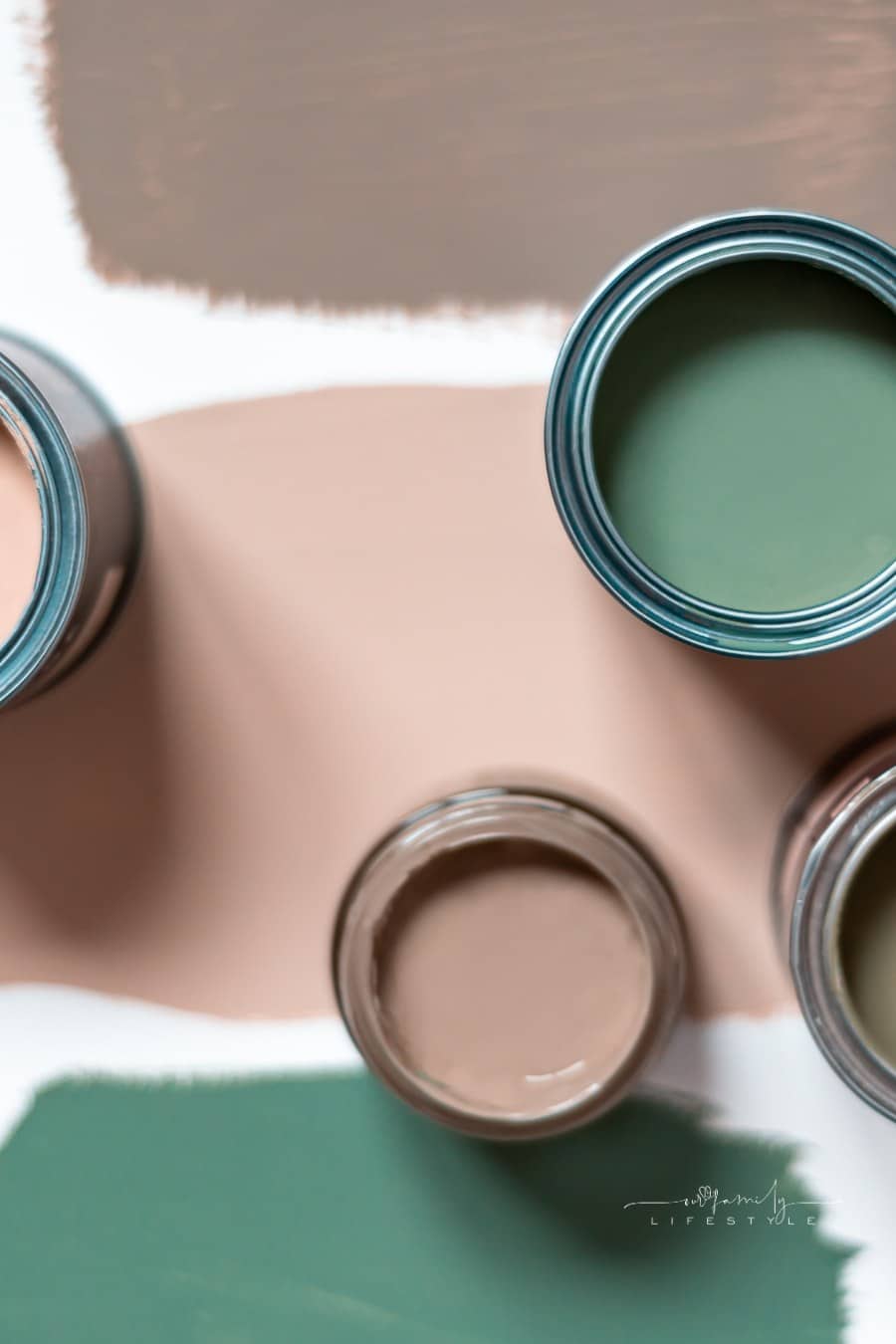Tiny sample paint cans during house renovation, process of choosing paint for the walls, different green colors, color charts on background