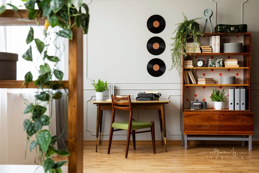 Black retro typewriter on a unique wooden desk, a mid-century modern chair and a renovated bookcase in a midcentury modern ho