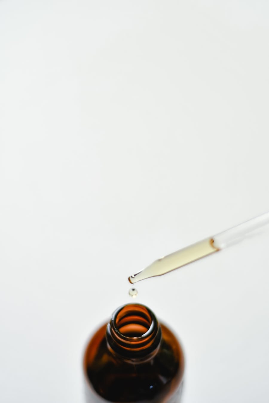Close-up of a brown glass dropper bottle with a droplet, perfect for essential oils or medicine use.