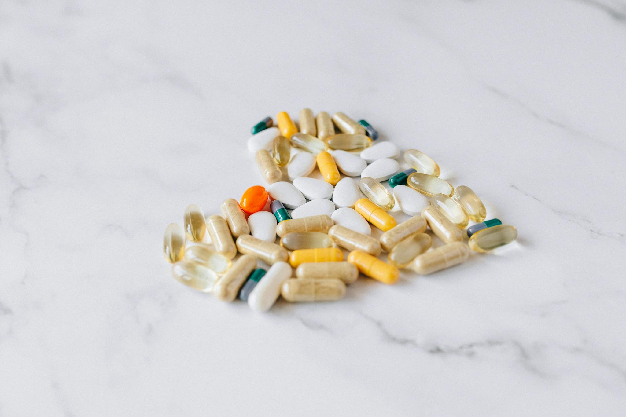 Close-up of various pills and supplements on a marble background, symbolizing health care and wellness.
