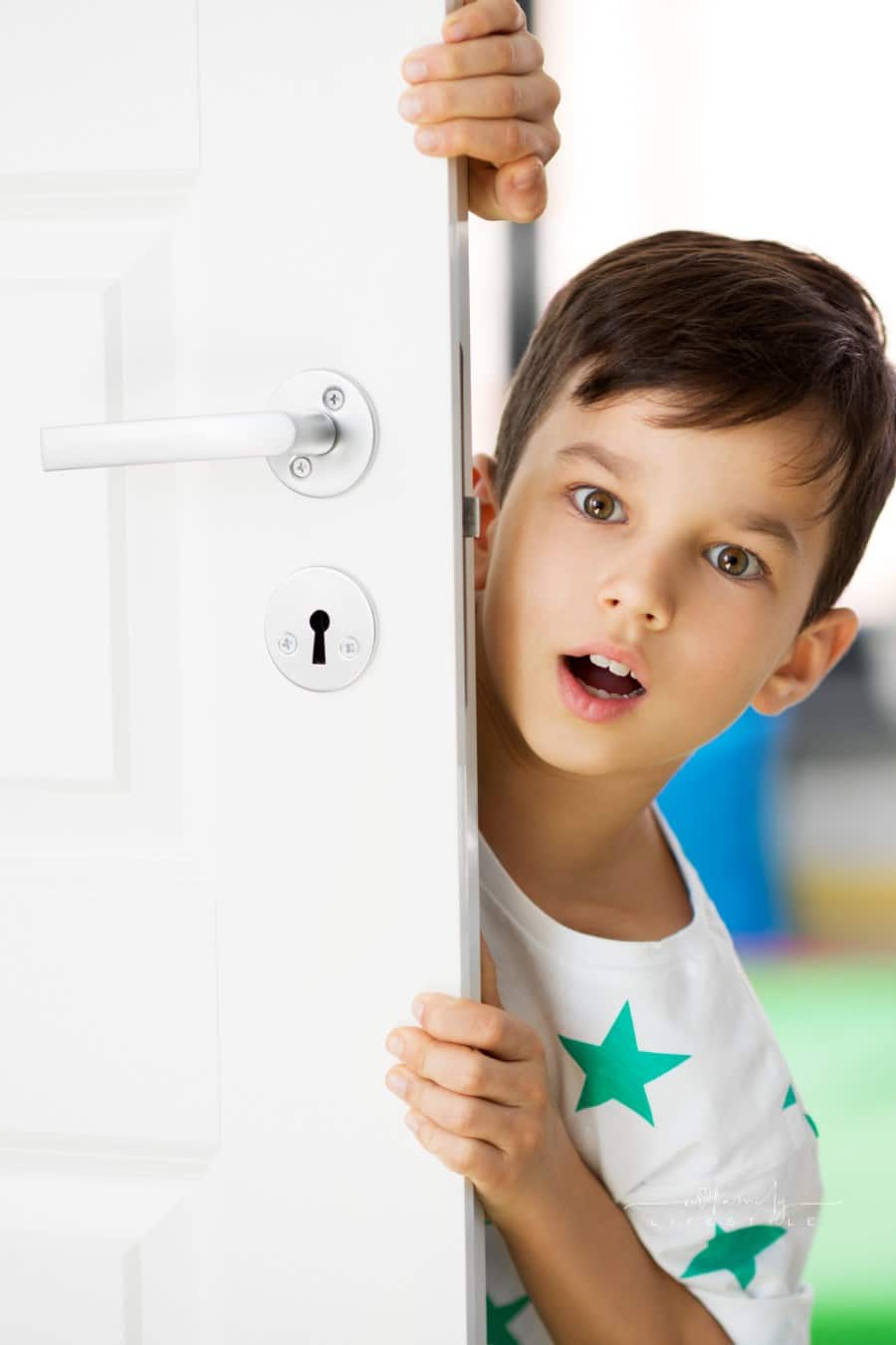 Surprised child peeking around an open door with open mouth and wide eyes