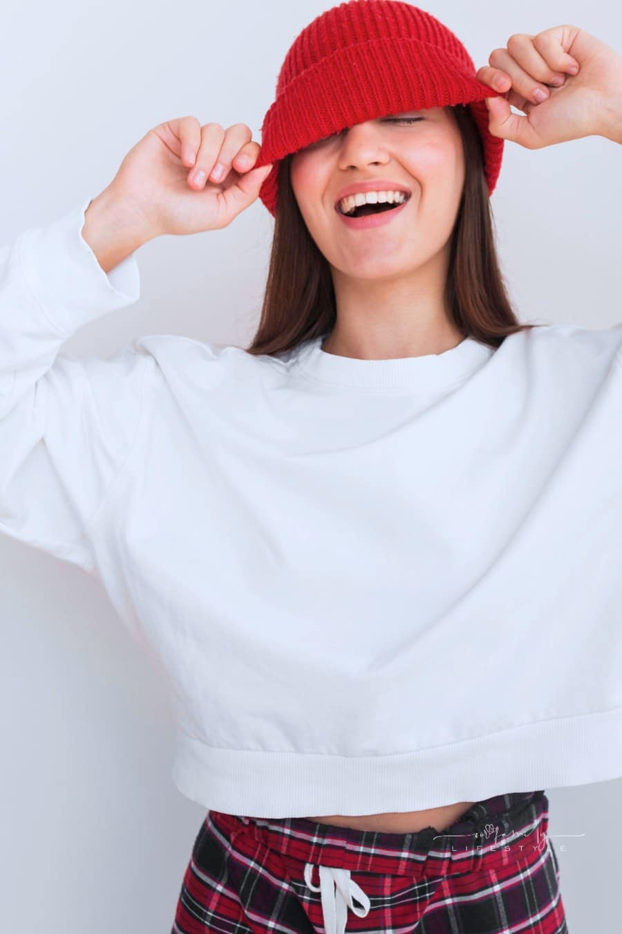 happy woman in white fleece sweatshirt and red beanie over her eyes