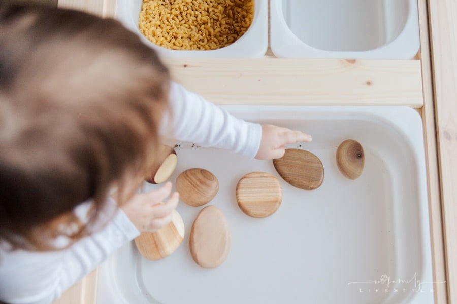 small child playing with wooden stones and dry pasta