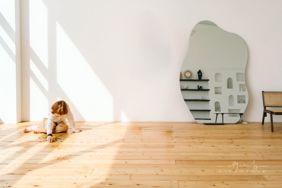 red-haired child putting a puzzle together on floor in shadow of large window