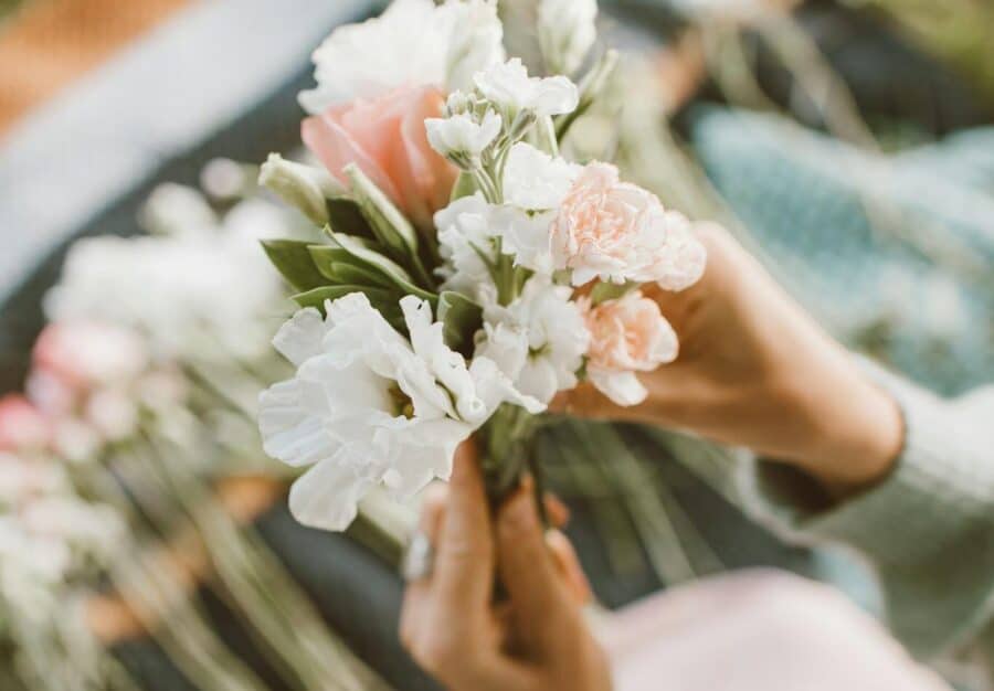 Creative close-up of hands arranging a vibrant flower bouquet in a garden setting.
