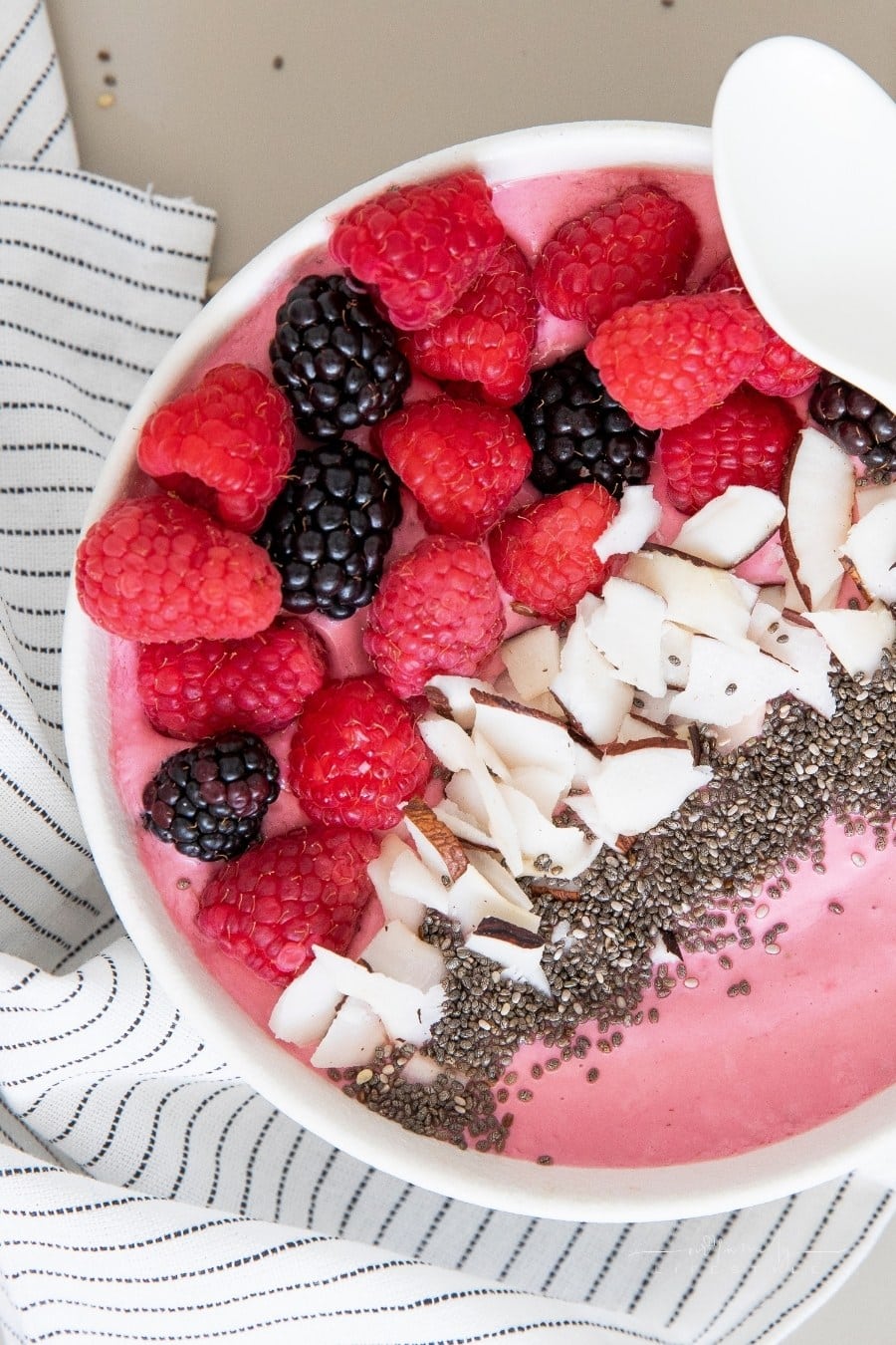 vegan smoothie bowl with raspberries, blackberries, coconut flakes, and flaxseed