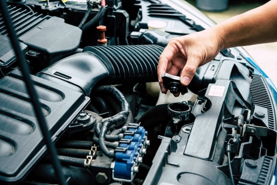man checking fluids under hood of a car