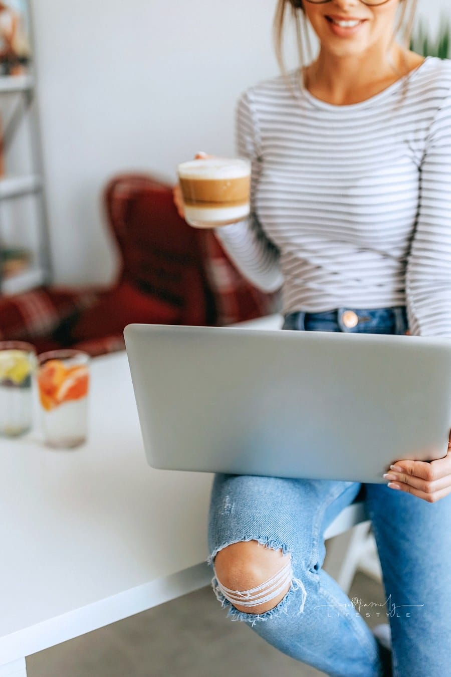Relaxed woman at home drinking coffee while looking at laptop