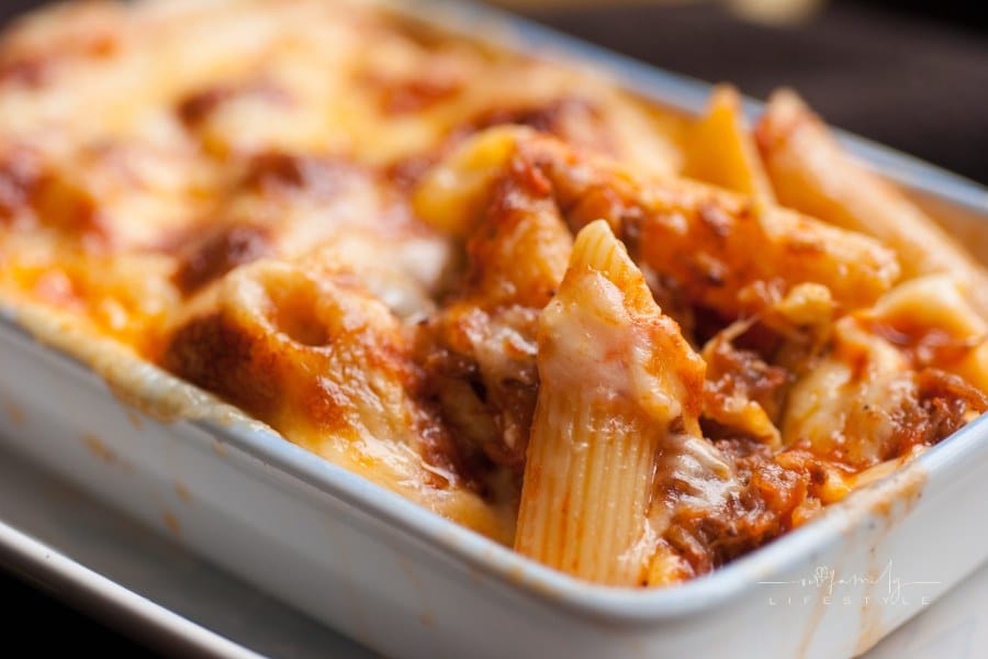 Baked penne pasta with tomato sauce and cheese in white bowl