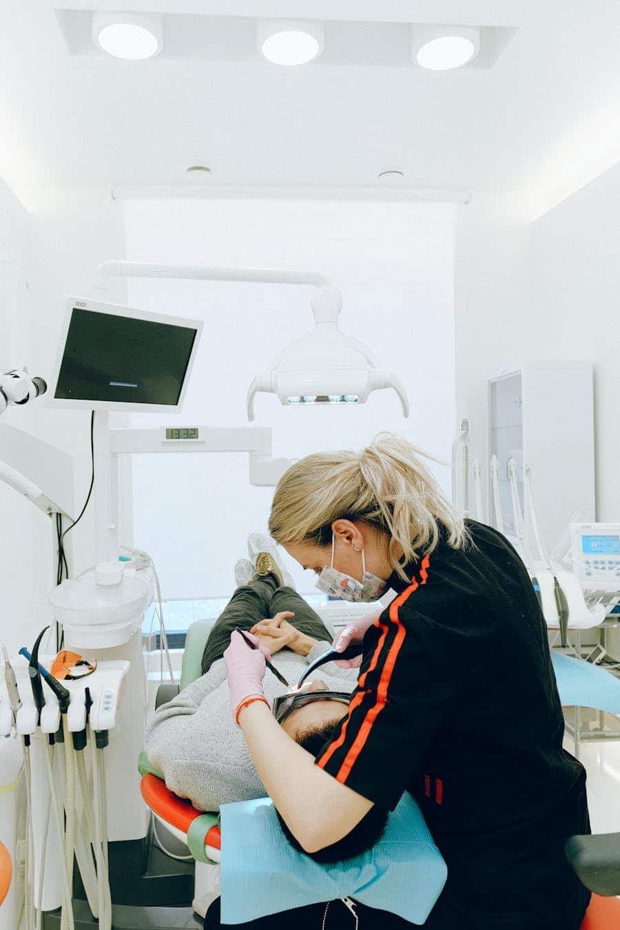 Dentist performing dental examination on patient in a modern clinic setting, ensuring dental hygiene and care.