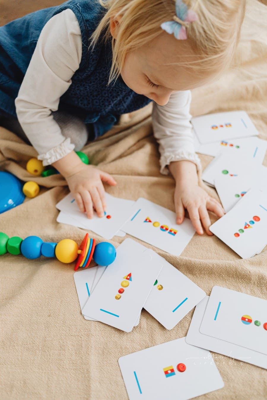 A Child Holding White Cards with Shapes and blocks