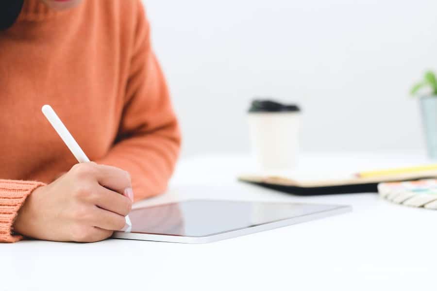 woman using iPad pencil to write in digital planner