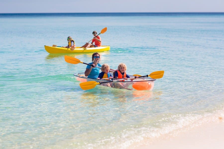Kids kayaking with mom in ocean. Family in kayak in tropical sea