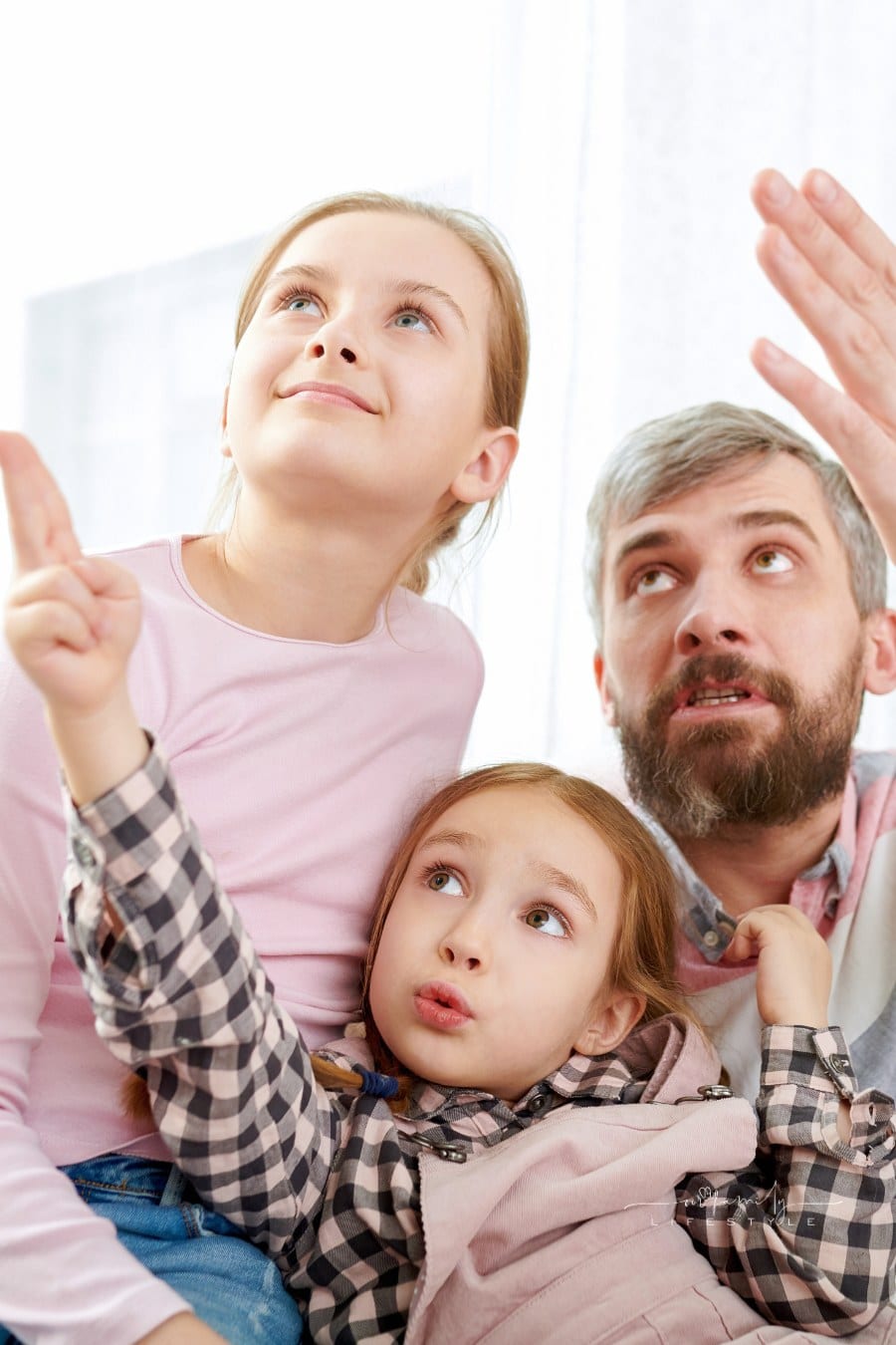 Loving Family in Living Room Gazing and Pointing at Something Above