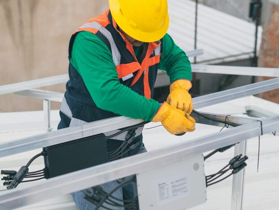 Electrician with PPE working on rooftop solar panel installation, focusing on safety.