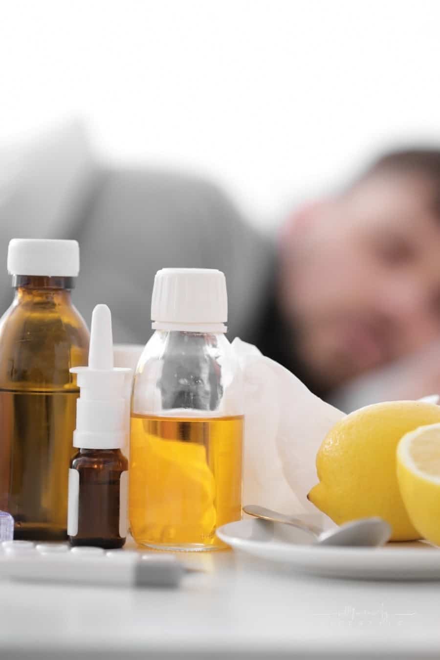OTC medicines on a table in frront of man sleeping off fever