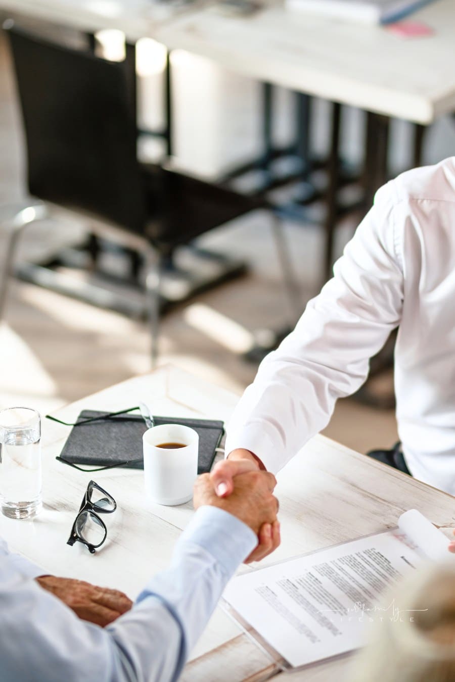 Above view of insurance agent and senior man shaking hands in the office.
