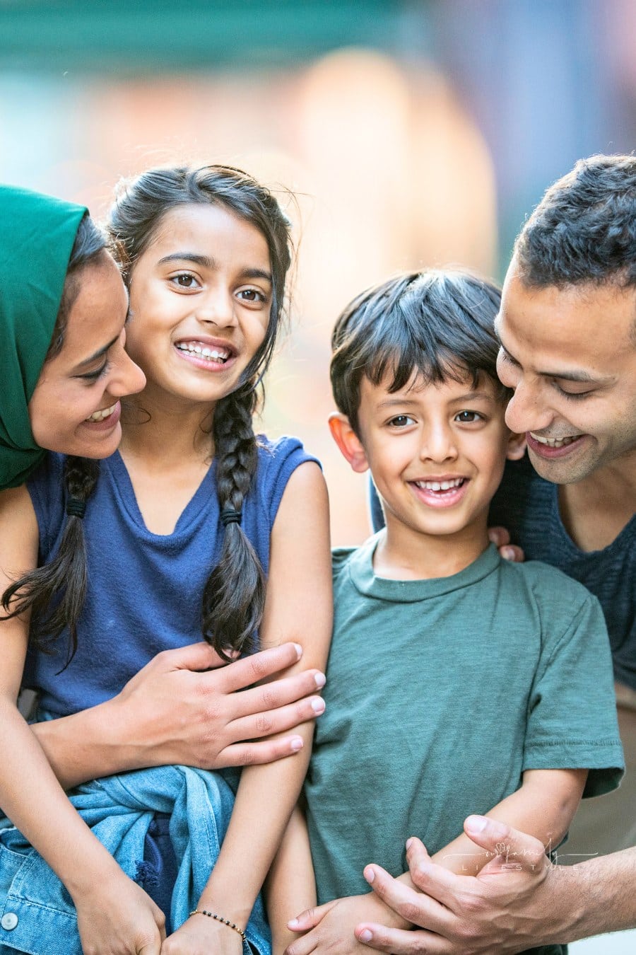 Muslim parents embracing their childlren; happy immigrant family