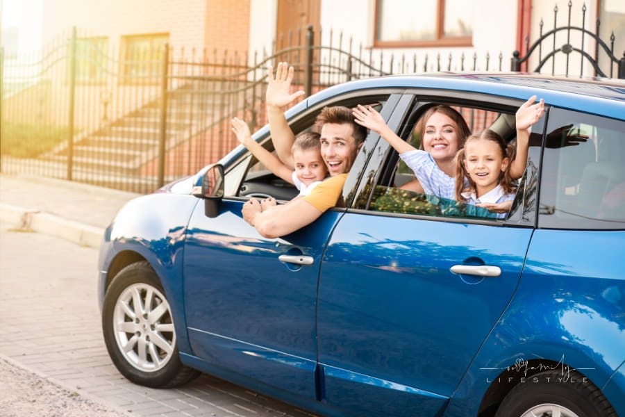 Happy Family Waving from Car Window on Road Trip