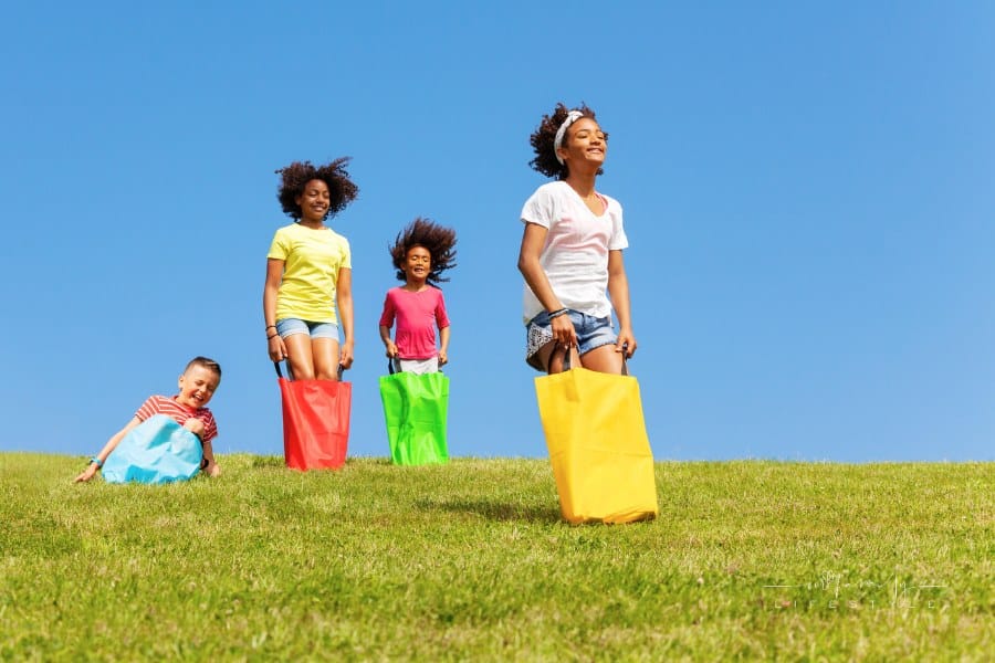 Kids Hop Downhill in Gunny Sack Race Game outside at field day games event