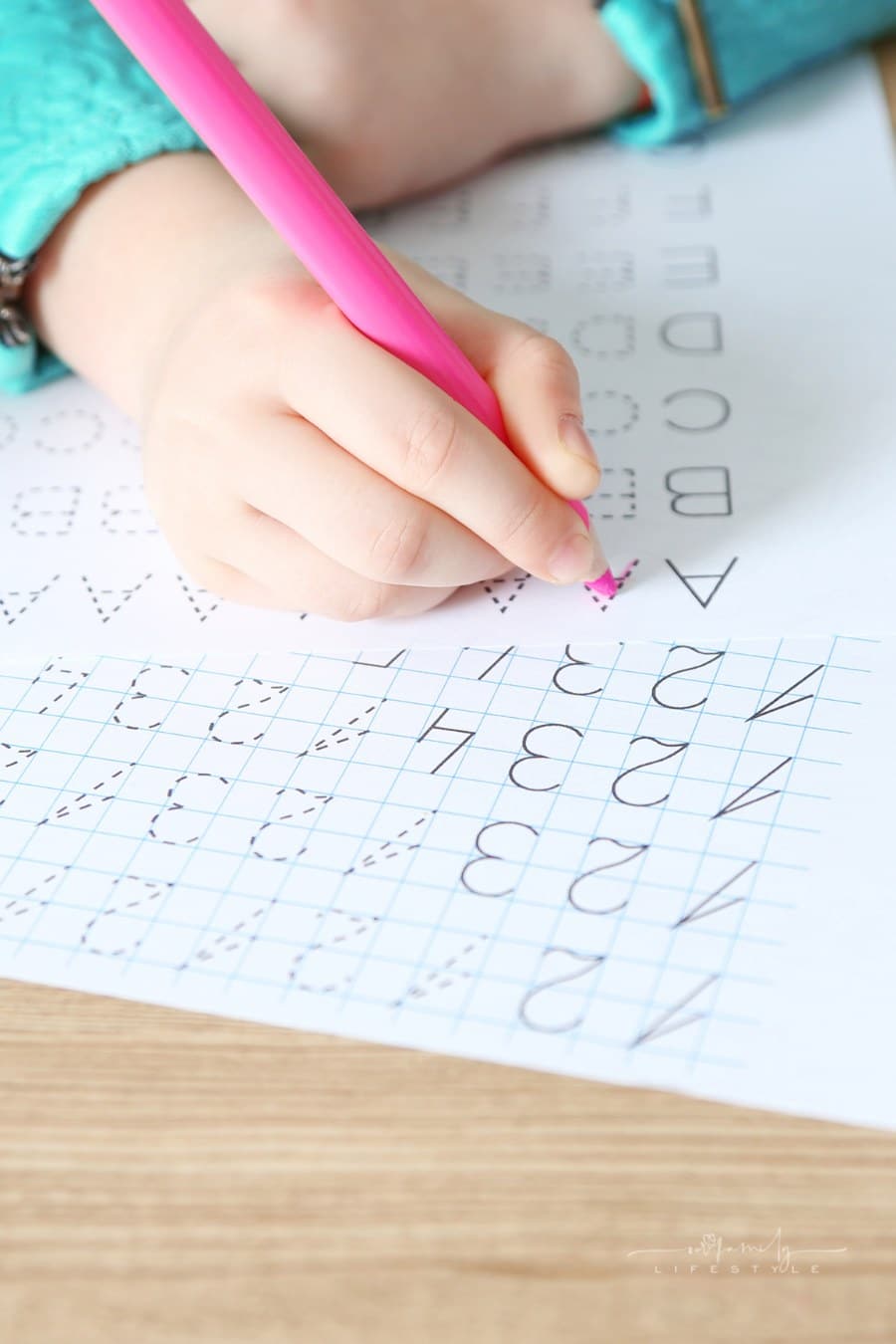 young girl tracing letters and numbers on worksheets