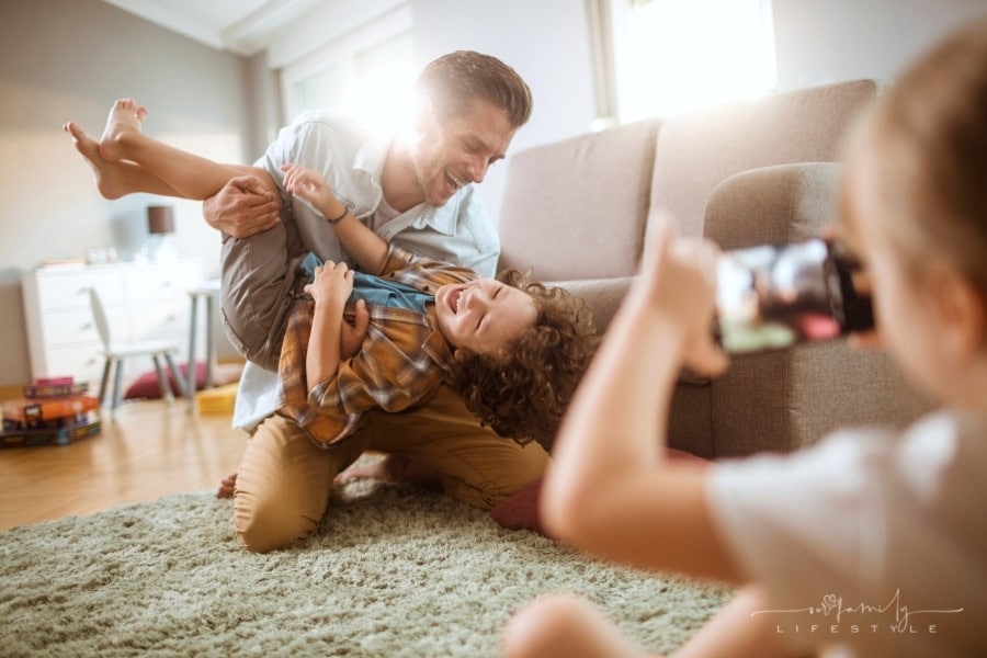dad and son playing with daughter taking a picture with smartphone
