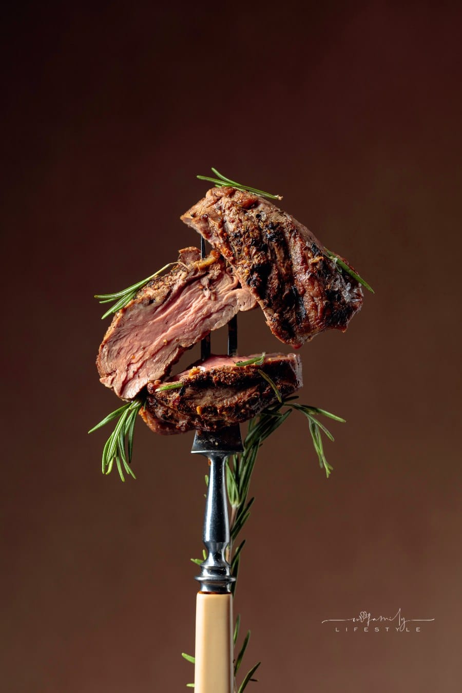 Grilled hot beef steak with rosemary on a fork