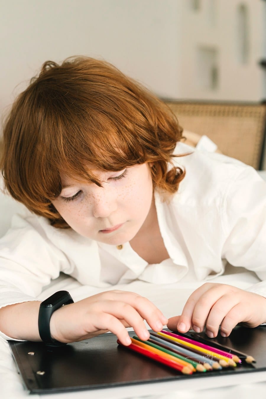 Photo of a Child with Red Hair Lining up Colored Pencils